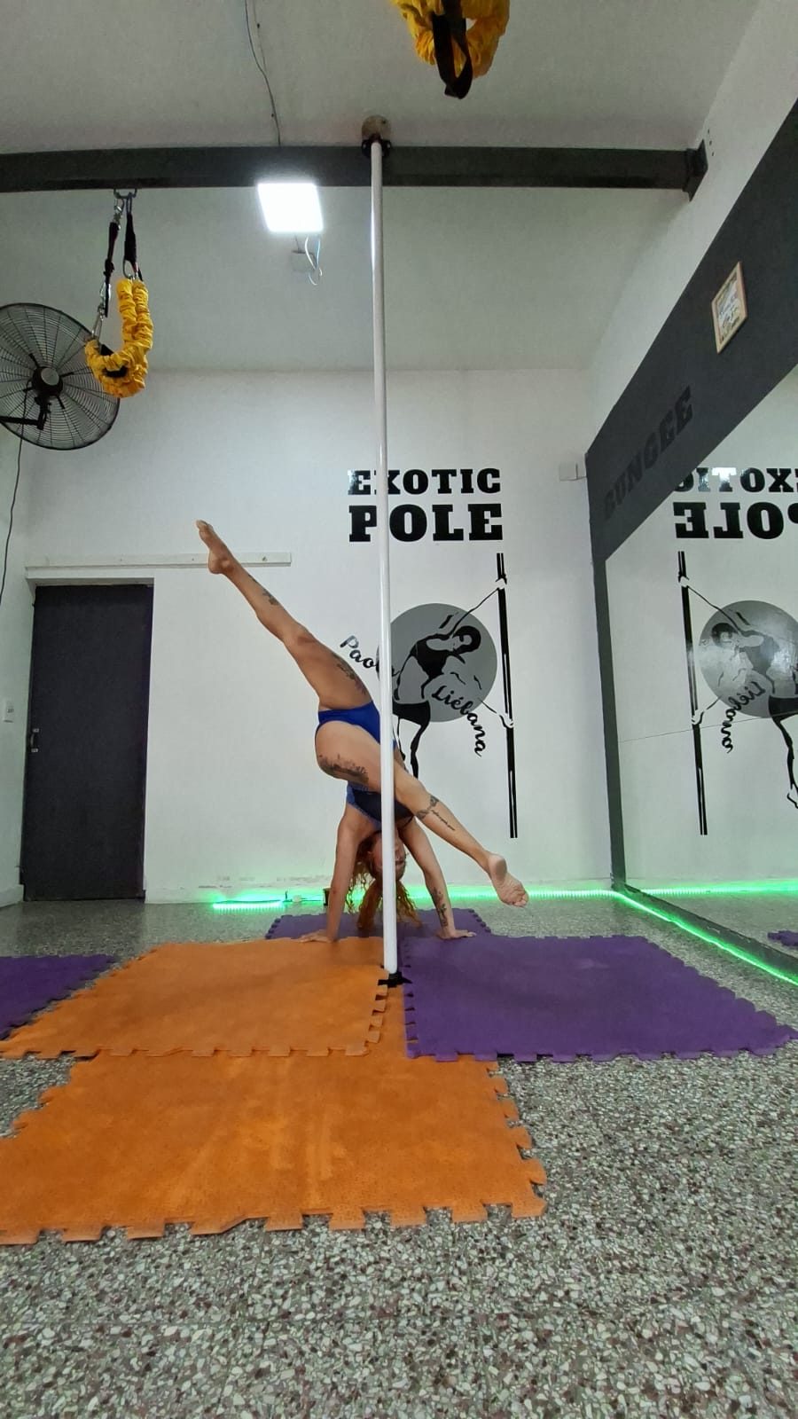 Sala de la sede de Pacheco con el mural EXOTIC POLE, colchonetas, ventiladores y los caños montados.